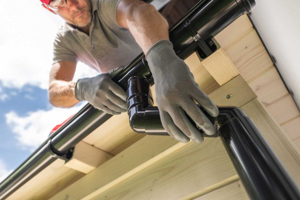 A professional installing gutters on a residential home